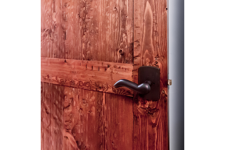 A reddish wooden door hangs open, with a soft, black lever-style handle.
